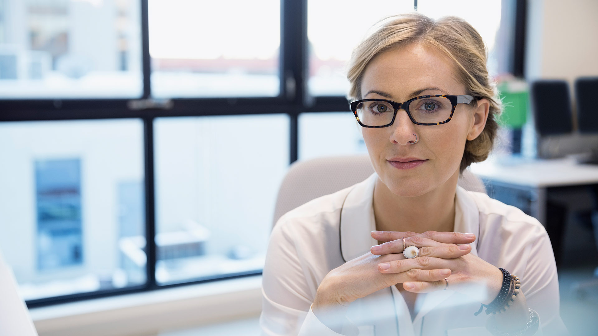 confident business woman with blonde hair sitting at office desk