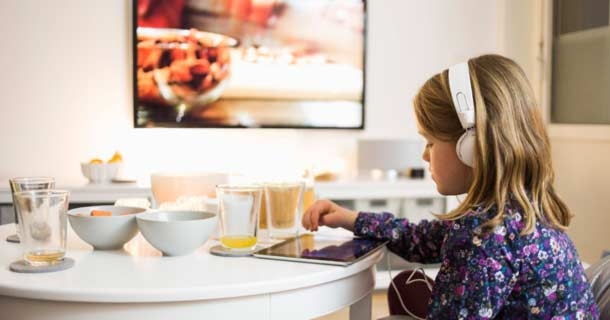 Young girl playing on tablet listening to headphones