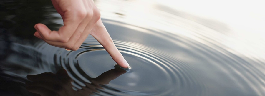 A person touching the water surface and creating ripples, water management, waste water