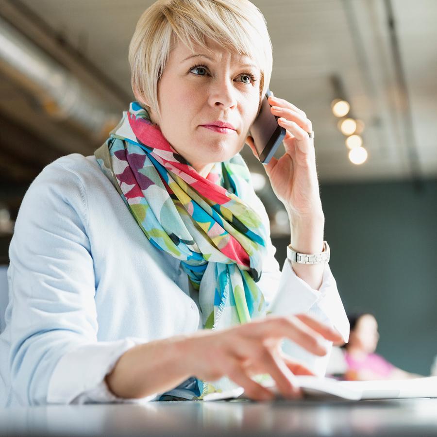 Female entrepreneur using mobile phone at desk.