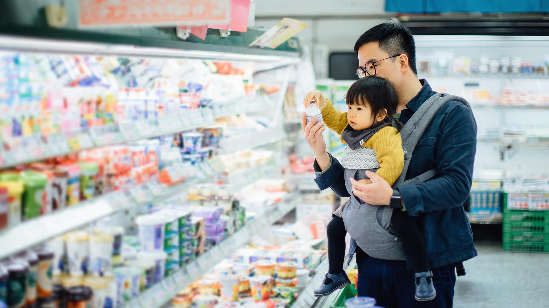 Asian father grocery shopping with cute little daughter in supermarket