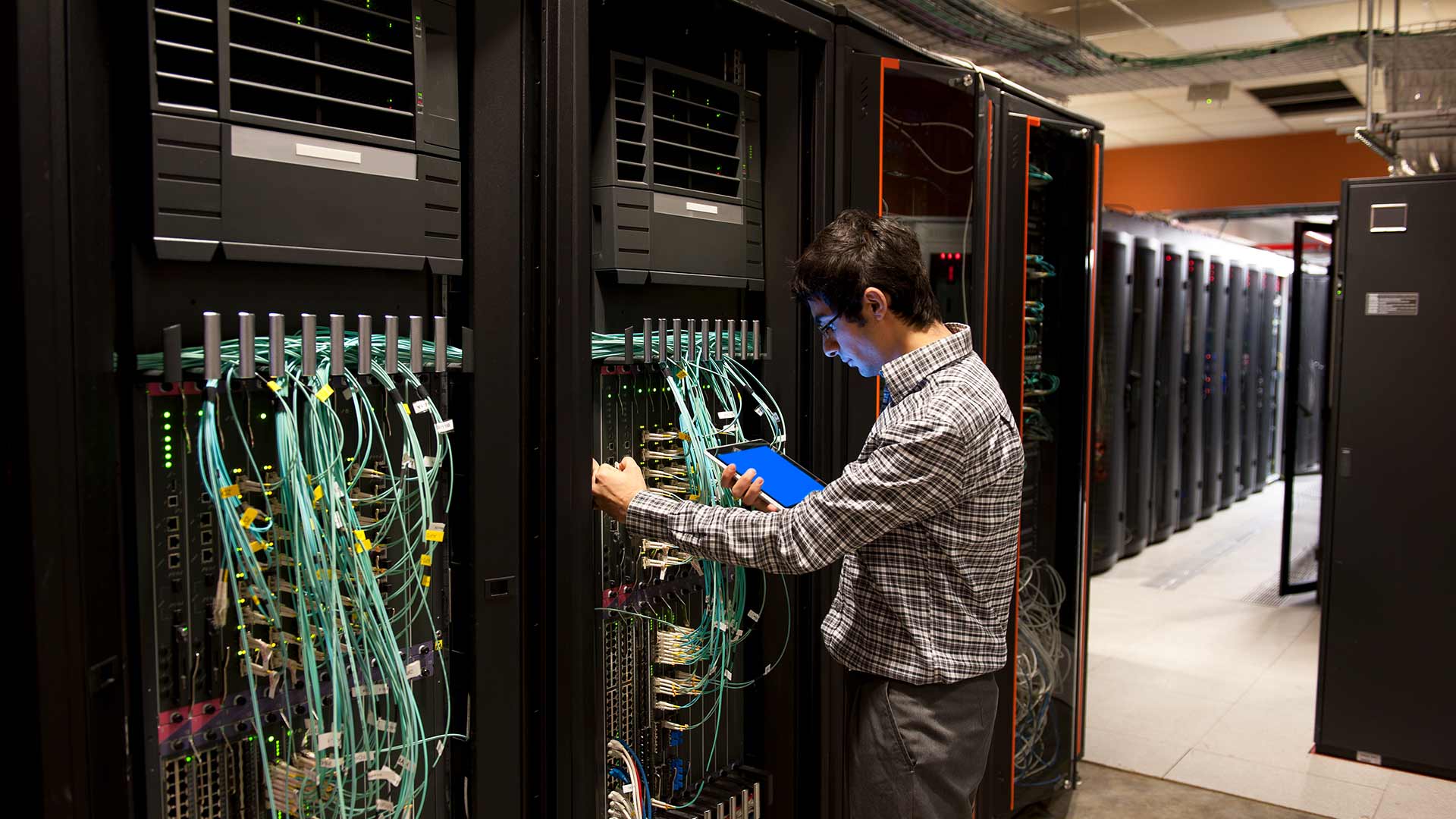 An IT technician programming computer equipment in a server room