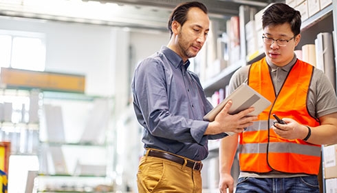 Two employees discussing while holding a digital tablet for remote monitoring and management of IT equipment