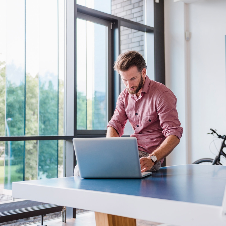 Boy sits on table while using laptop at office