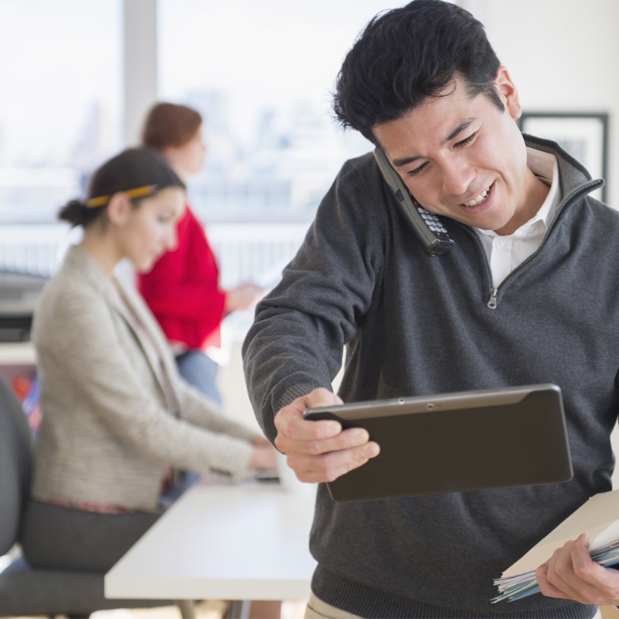 Man looking at tablet while talking on Mobile phone