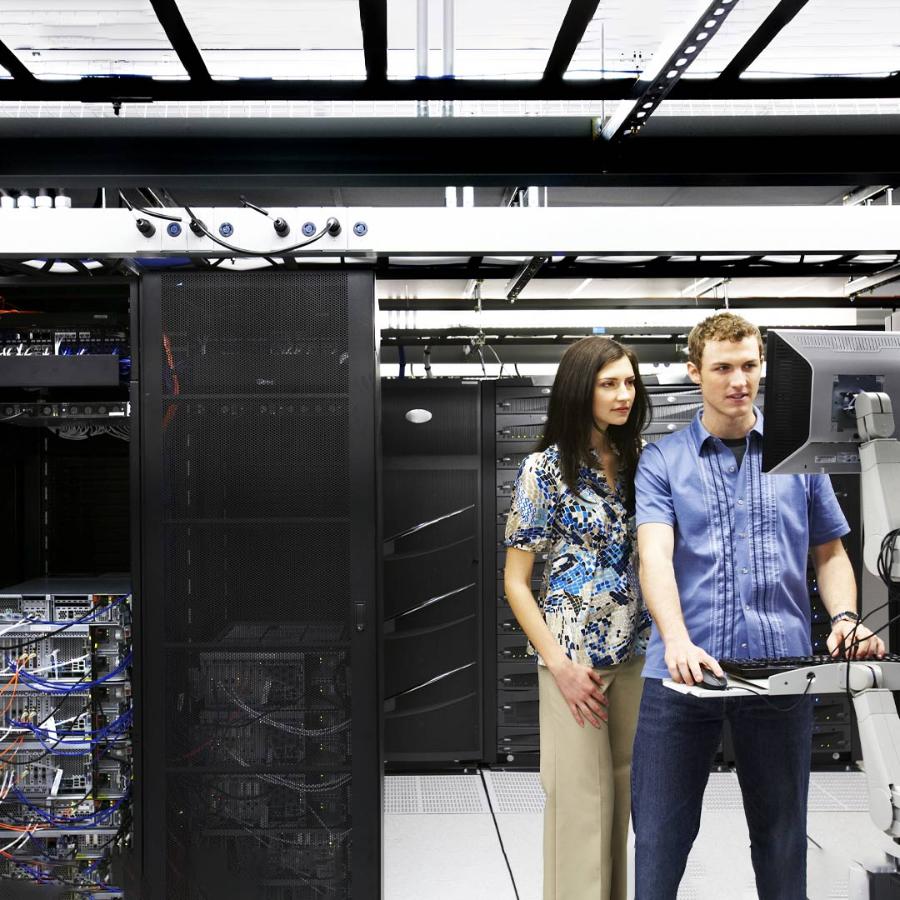Man and woman looking at computer in server room. Technicians, data storage, information technology