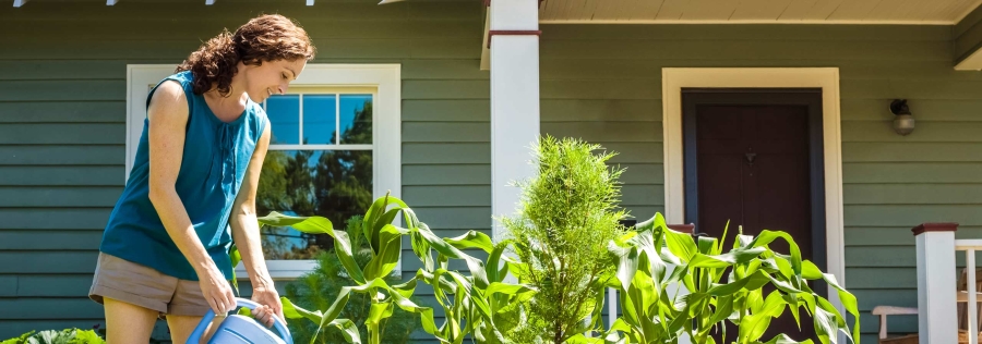 Woman watering garden outside of her home