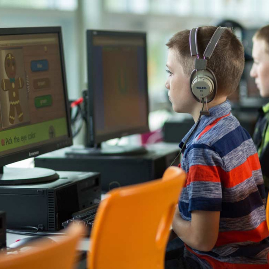kid wearing headphones and using computer